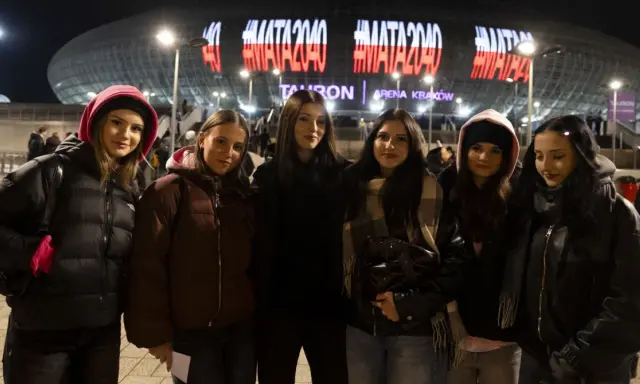 Grupa młodych kobiet czeka na koncert Maty w Krakowie. Na Tauron Arenie świeci napis #MATA2040.
