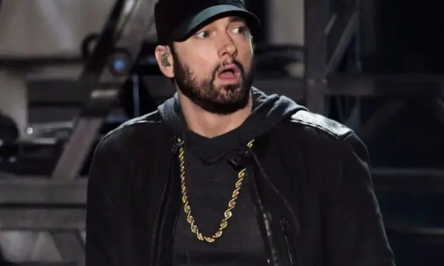 Eminem w czapce i złotej koli, z miną sugerującą zdziwienie, jakby usłyszał pytanie: czemu Eminem nie lubi Polski.