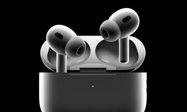 Białe słuchawki AirPods Pro w etui z zieloną diodą, na czarnym tle.