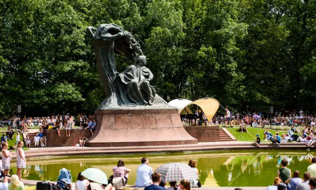 Koncert chopinowski w Łazienkach Królewskich. Tłumy słuchają muzyki przy pomniku Chopina.