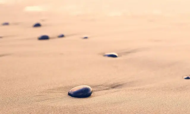 Spacer dzika plaża. Kamienie na piasku, szum fal. Kto śpiewa? Może wiatr?