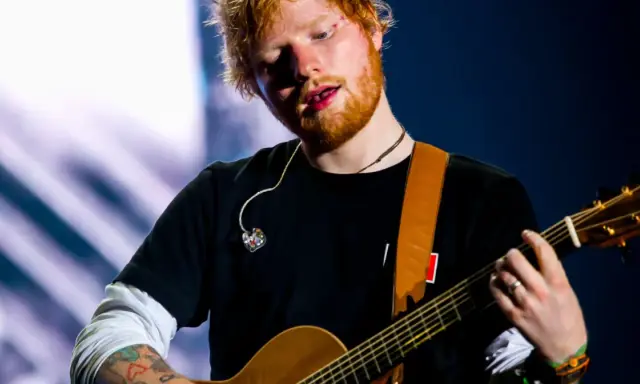 Ed Sheeran gra na gitarze, a jego wiek to 33 lata.