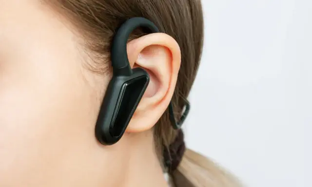 Czarna słuchawka bluetooth na uchu, idealna do rozmów w biegu.