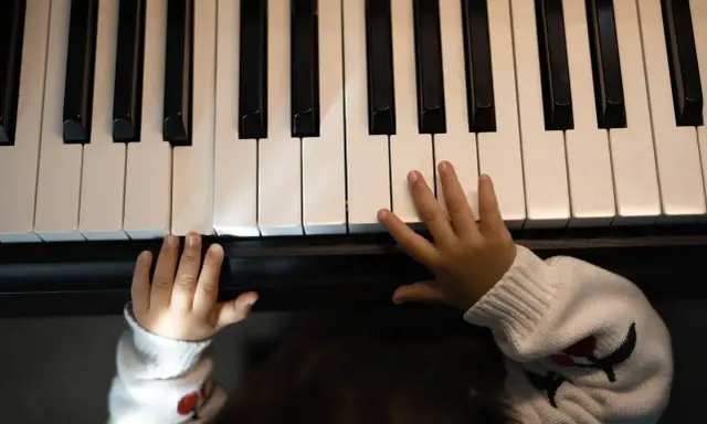 Małe rączki na klawiaturze pianina, jakby szukały melodii, która tworzy teksty piosenek które dają do myślenia.