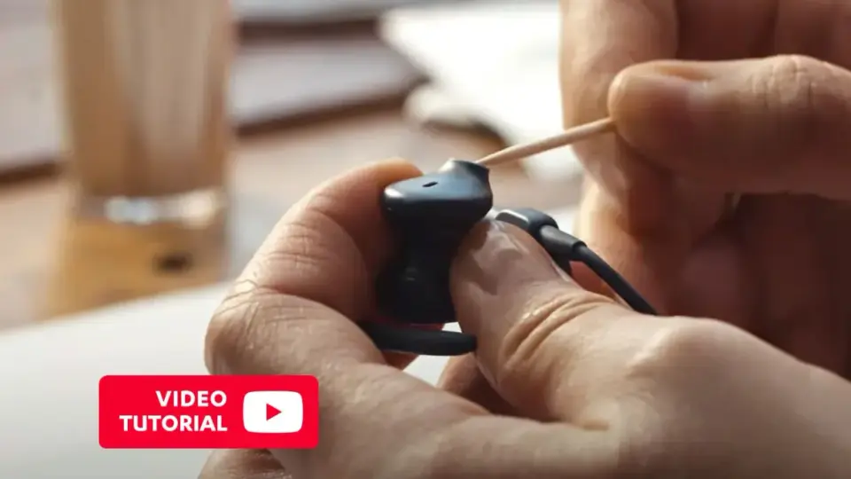 Ręce czyszczą słuchawki douszne wykałaczką. Dowiedz się, jak wyczyścić słuchawki douszne, oglądając ten tutorial.