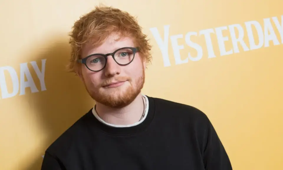 Ed Sheeran w okularach i czarnej bluzie, na tle napisu "YESTERDAY". Wygląda jakby zastanawiał się, kiedy urodził się Ed Sheeran.