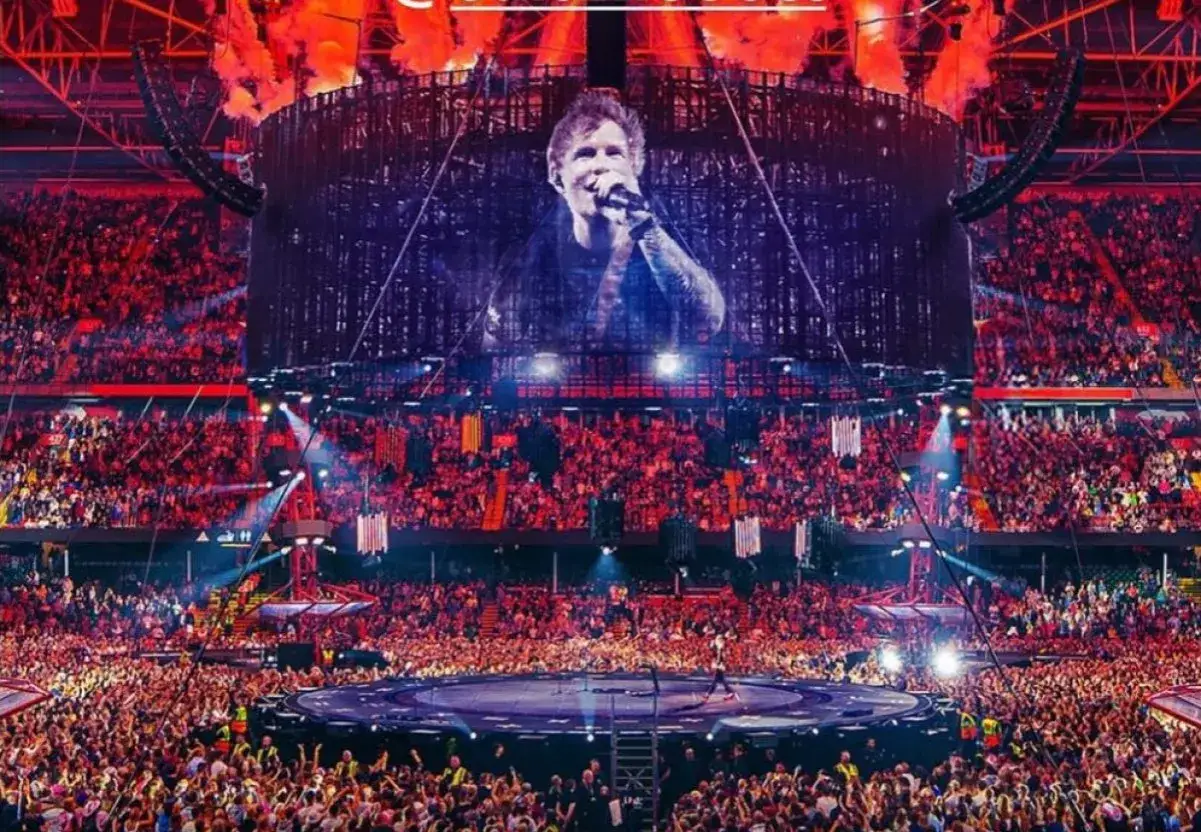 Ed Sheeran na scenie stadionu, tłumy ludzi, pirotechnika. Zastanawiasz się, ile Ed Sheeran bierze za koncert?