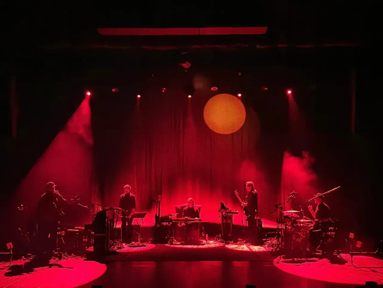 Zespół gra na scenie w czerwonym świetle. Zastanawiasz się, ile trwa koncert korteza?