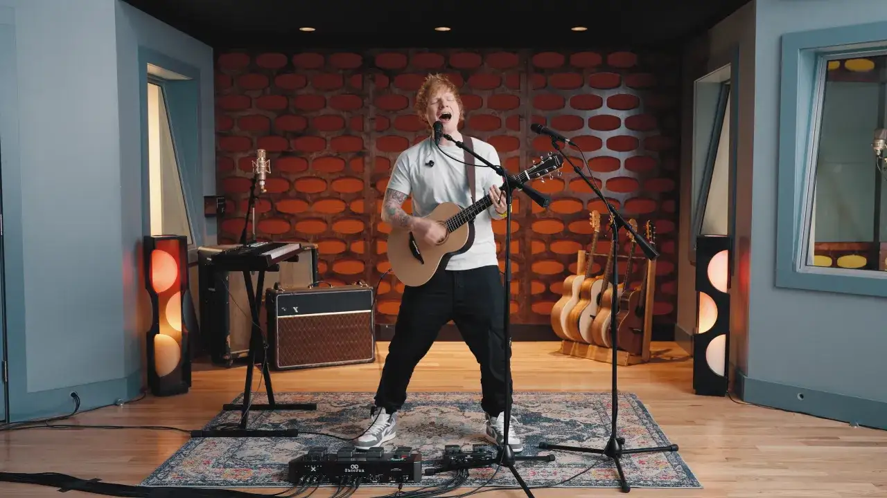 Ed Sheeran śpiewa i gra na gitarze akustycznej. Na czym gra Ed Sheeran? Na swoim charakterystycznym modelu gitary, z pętlą efektów pod stopami.